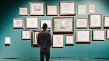 person som tittar på tavlor i ett galleri