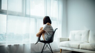 girl sitting on a chair looking out through the window