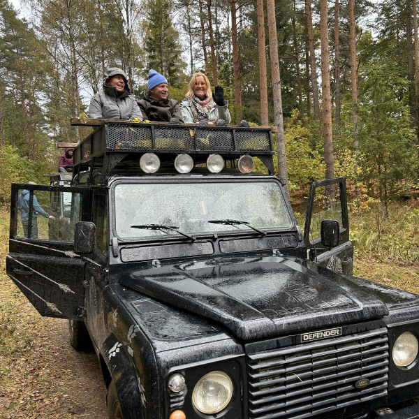 Tre människor i en svart Jeep. De ser mot kameran och ler.