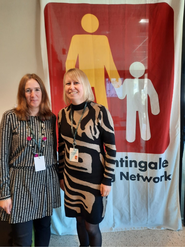 Två kvinnor står bredvid varandra och ser leende in i kameran.