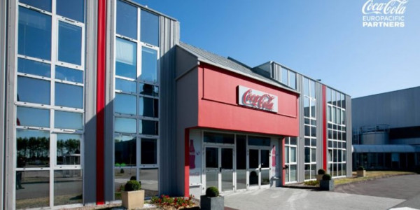 A modern looking building with many windows and the Coca Cola logo above the entrance.