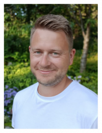 A blond man smiling at the camera.