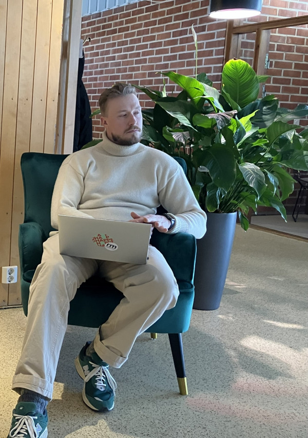 En man sitter i en fåtölj med en laptop i knät.