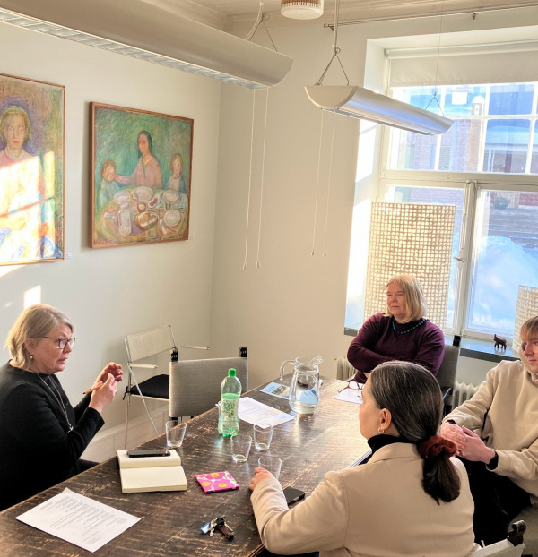 Fyra människor sitter runt ett mötesbord.