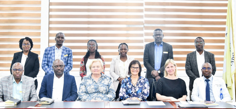 Gruppbild av personer i ett mötesrum. Alla ser in i kameran.