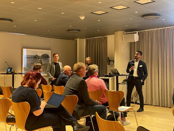 A man talks in front of a room of spectators.