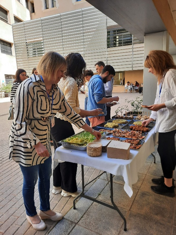 People serving themselves lunch from a buffet table outdoors.