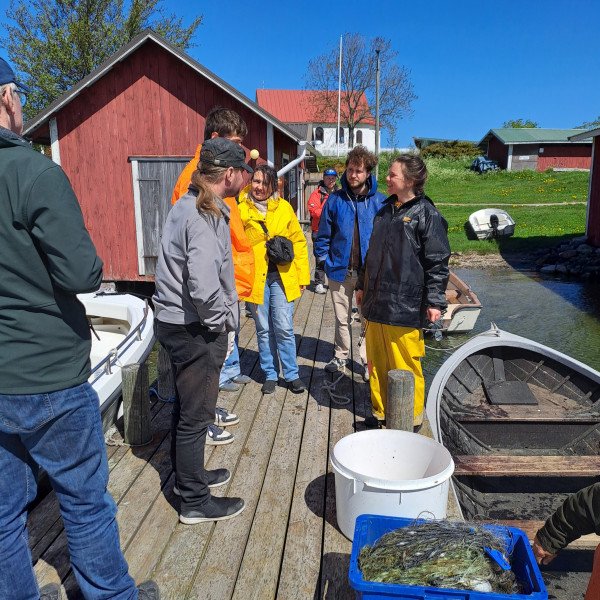A group of people on a pier surrounded by fishing equipment.