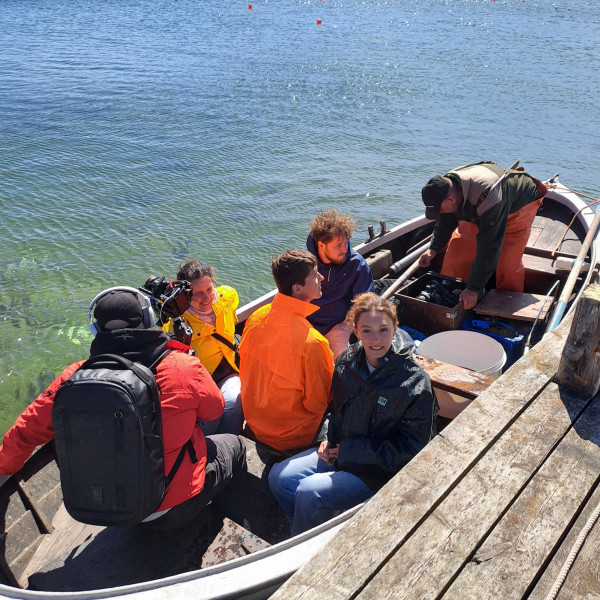 A group of people sitting in a boat next to a pier