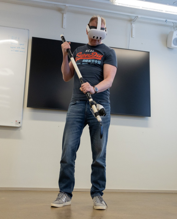 En man med VR-headset på huvudet håller i en håv.