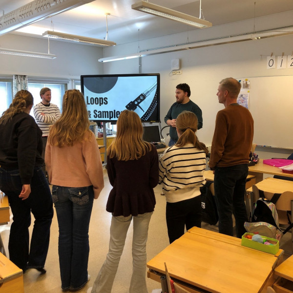 Två män håller en presentation för en liten grupp. Gruppen står med ryggen mot kameran. 