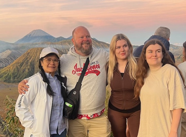 A picture of four people, three women and one man. They are all looking forward, to the right of the photographer, and smiling.